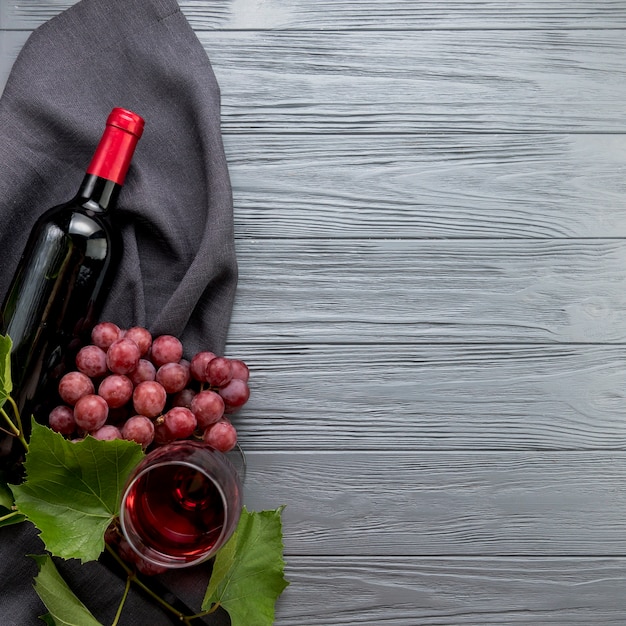 Bovenaanzicht fles wijn met glas en een tros druiven