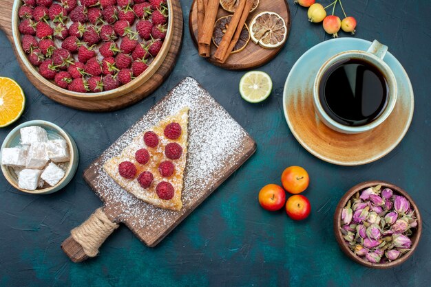 Bovenaanzicht fluitje van een cent gebakken snoepje met frambozen en thee op donkere bureau bessen cake taartkoekje