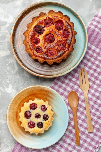 Bovenaanzicht frambozencake heerlijk met kleine cake op het grijs-lichte bureau taart taart bakken fruit zoet