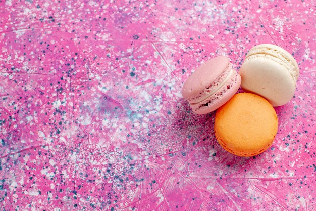 Bovenaanzicht Franse macarons heerlijke kleine cakes op het roze bureau bak cake zoete suikertaart confituur