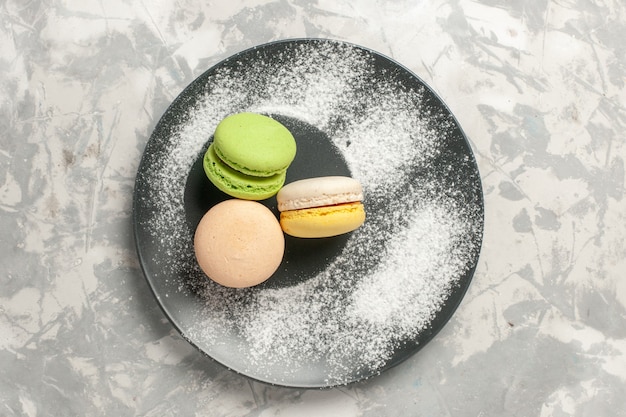 Gratis foto bovenaanzicht franse macarons kleine heerlijke taarten op wit oppervlak koekje suiker cake zoete taart thee koekje