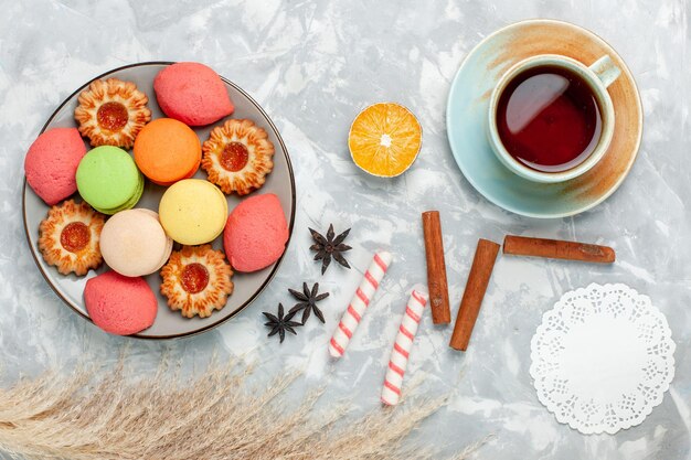 Bovenaanzicht Franse macarons met koekjes en thee op lichtwit bureau