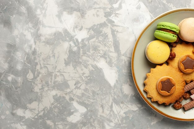 Bovenaanzicht Franse macarons met taarten en koekjes op witte bureaukoekjes biscuit suiker cake zoete taart