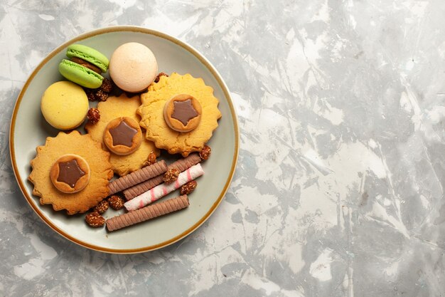 Bovenaanzicht franse macarons met taarten en koekjes op witte ondergrond koekjes biscuit suiker cake zoete taart