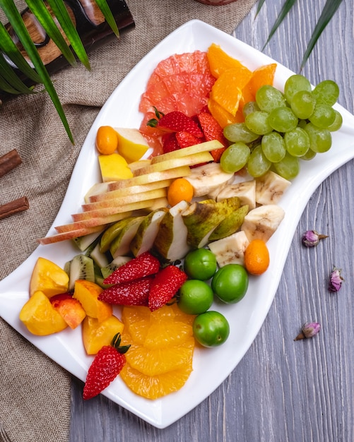 Bovenaanzicht fruitschaal oranje aardbei banaan kiwi peren druiven en kersenpruim