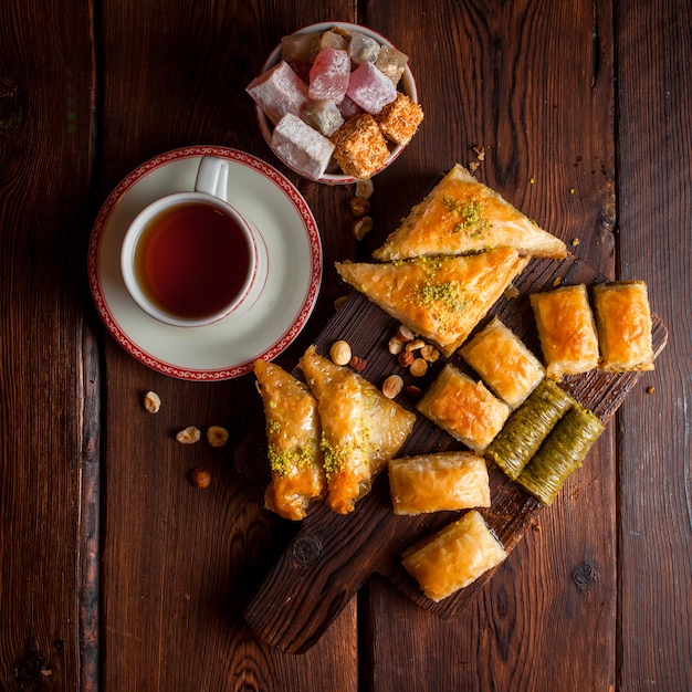 Bovenaanzicht geassorteerde Turkse baklava met kopje thee en Turks fruit in houten plank