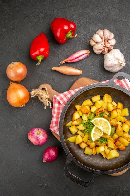 Bovenaanzicht gebakken aardappelen in pan met citroen op de donkere achtergrond