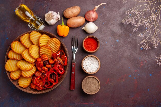 Bovenaanzicht gebakken aardappelen met verschillende kruiden op een donker bureau