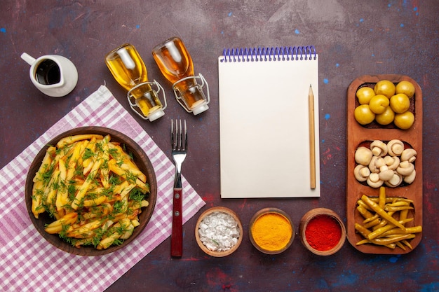 Bovenaanzicht gebakken aardappelen smakelijke frietjes met greens en olie op het donkere oppervlak