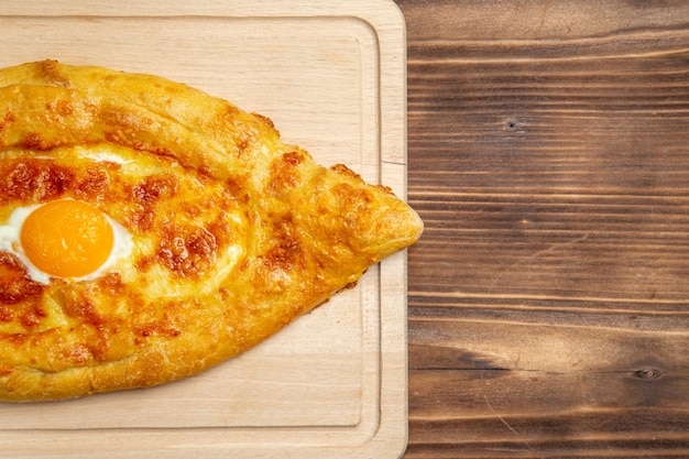 Bovenaanzicht gebakken brood met gekookt ei op het bruine houten oppervlak brood broodje voedsel ei ontbijtdeeg