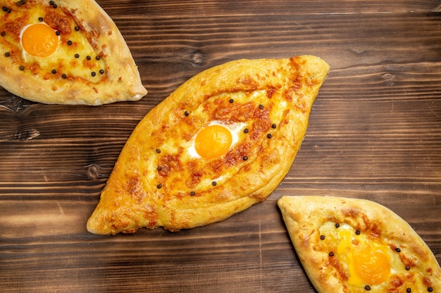 Bovenaanzicht gebakken eierbrood op het bruine oppervlak deeg ei brood broodje ontbijt