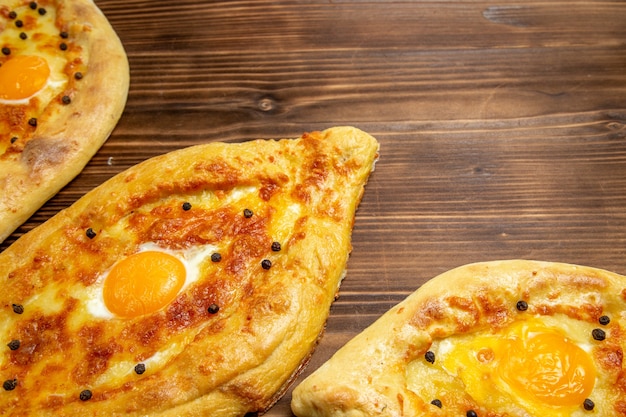 Bovenaanzicht gebakken eierbrood vers uit de oven op bruin houten bureau deeg ei brood broodje ontbijt