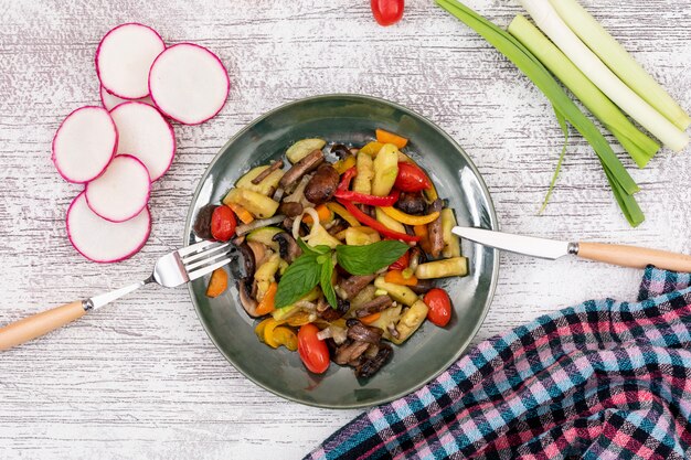 Bovenaanzicht gebakken groente salade champignon cherry tomaat rode paprika gele peper met mes en vork