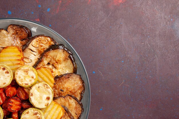 Bovenaanzicht gebakken groenten aardappelen en aubergines vers uit de oven op donkere ruimte