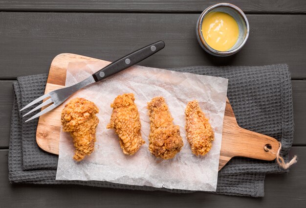 Bovenaanzicht gebakken kippenvleugels op snijplank met saus