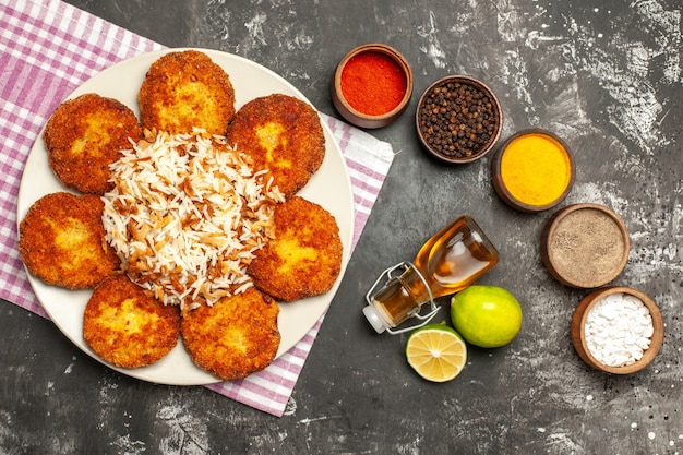 Bovenaanzicht gebakken schnitzels met gekookte rijst en kruiden op donkere ondergrond voedsel vlees rissole