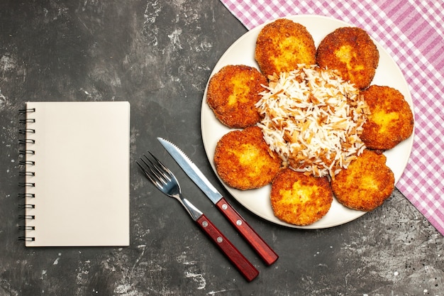 Bovenaanzicht gebakken schnitzels met gekookte rijst op de donkere plaat vleesgerecht