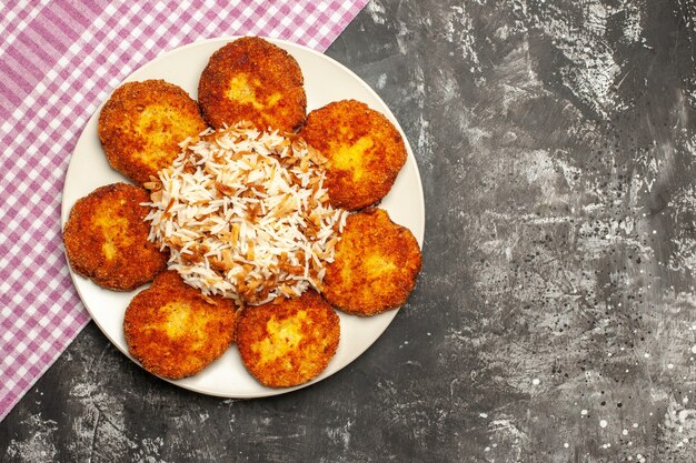 Bovenaanzicht gebakken schnitzels met gekookte rijst op donkere oppervlak vleesgerecht rissole