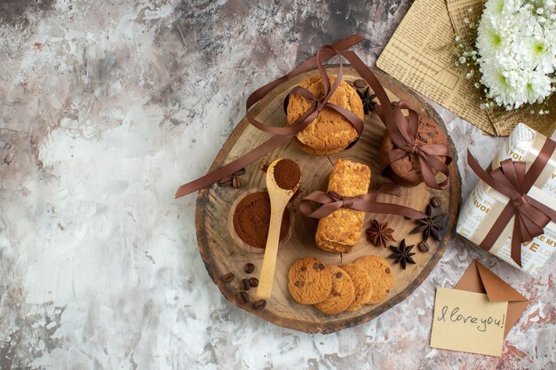 Bovenaanzicht gebonden koekjes cacao in kom op houten bord bloemboeket liefdesbrief op tafel