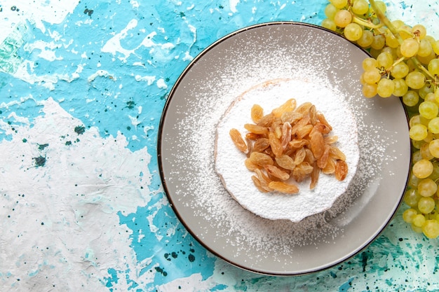 Gratis foto bovenaanzicht gedroogde rozijnen van druif met verse groene druiven op lichtblauwe oppervlakte droge rozijnen fruit kleurenfoto