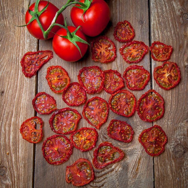 Bovenaanzicht gedroogde tomaten en verse tomaten op houten tafel