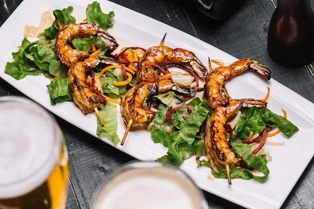 Bovenaanzicht gegrilde garnalen op een stokje met salade bladeren