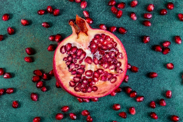 Bovenaanzicht gehakte halve granaatappel met geschild op een groene tafel