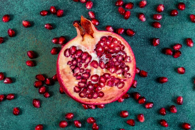 Bovenaanzicht gehakte halve granaatappel met geschild op een groene tafel