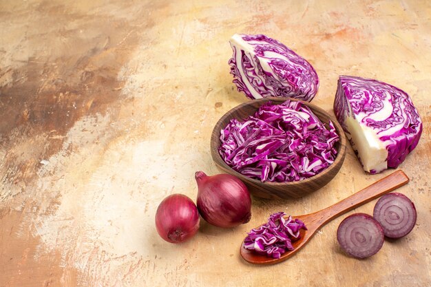 Bovenaanzicht gehakte rode kool in een houten kom en verschillende uien zijn klaar voor bietensalade op een houten ondergrond met ruimte voor tekst