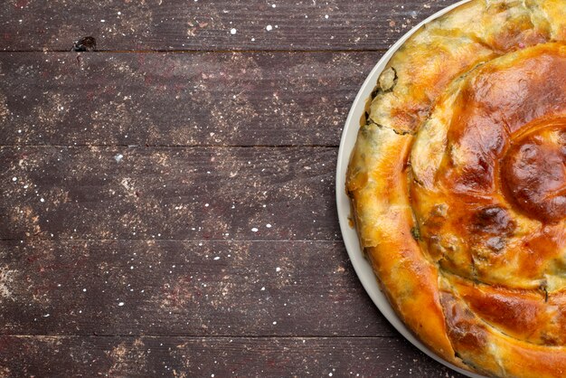 Bovenaanzicht gekookt greens gebak ronde binnen witte plaat op de bruine houten bureau maaltijd eten gebak lunch greens