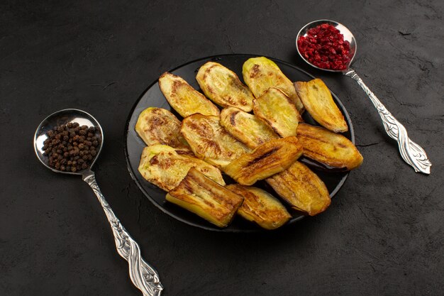 bovenaanzicht gekookte aubergines gesneden in zwarte plaat op het donker