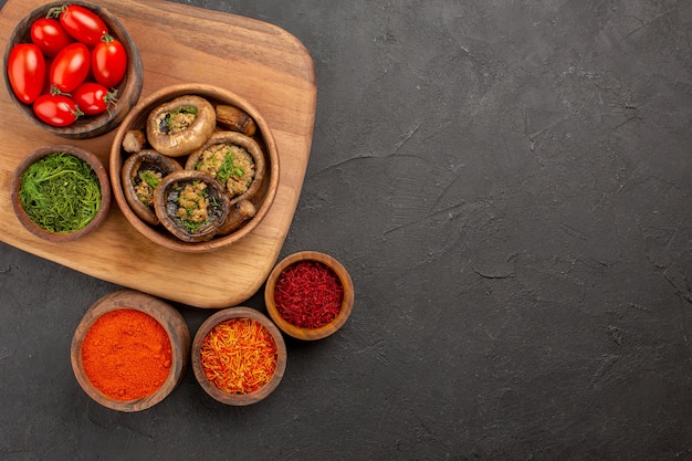 Gratis foto bovenaanzicht gekookte champignons met kruiden op donkere tafel eten wild rijp