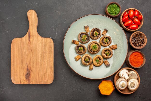 Bovenaanzicht gekookte champignons met tomaten en kruiden op het donkere oppervlak schotel maaltijd koken paddestoel diner