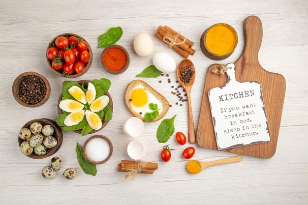 Bovenaanzicht gekookte eieren met tomaten en kruiderijen op witte achtergrond foto ochtendmaaltijd ontbijt lunch kleur voedselsalade