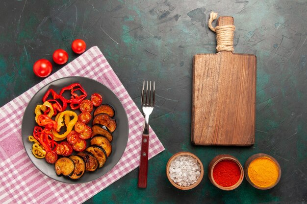 Bovenaanzicht gekookte gesneden groenten paprika en aubergines met kruiden op het groene oppervlak