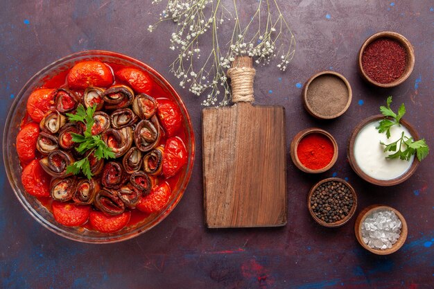 Bovenaanzicht gekookte groentemaaltijd heerlijke tomaten en aubergines met kruiden op het donkere oppervlak
