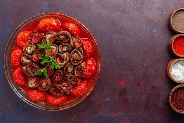 Bovenaanzicht gekookte groentemaaltijd heerlijke tomaten en aubergines met kruiden op het donkere oppervlak