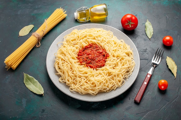 Bovenaanzicht gekookte italiaanse pasta met gehakt tomatenvlees op het donkerblauwe bureau