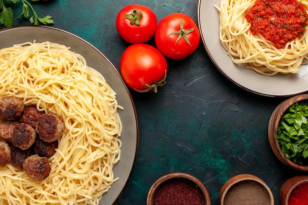 Bovenaanzicht gekookte italiaanse pasta met vlees en kruiden op het donkerblauwe oppervlak