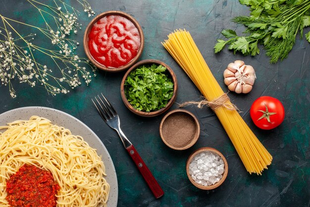 Bovenaanzicht gekookte Italiaanse pasta met vlees en verschillende kruiden op het blauwe oppervlak