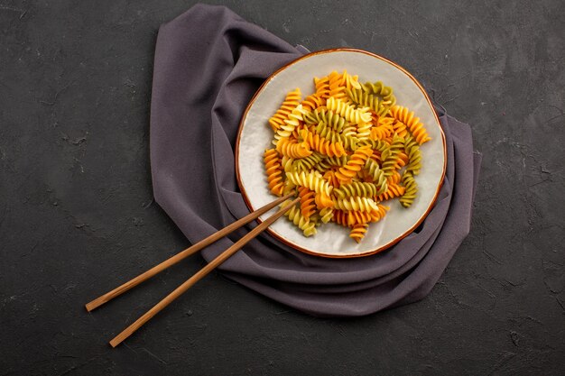 Bovenaanzicht gekookte Italiaanse pasta ongebruikelijke spiraal pasta binnen plaat op de donkere ruimte