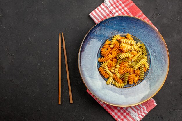 Bovenaanzicht gekookte Italiaanse pasta ongebruikelijke spiraal pasta binnen plaat op de donkere ruimte