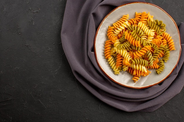 Bovenaanzicht gekookte Italiaanse pasta ongebruikelijke spiraal pasta binnen plaat op de donkere ruimte
