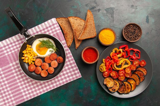 Bovenaanzicht gekookte paprika met aubergines ontbijt en verschillende kruiden op groene ondergrond