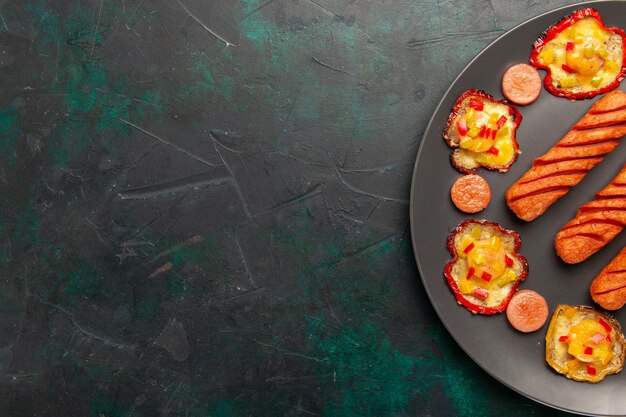 Gratis foto bovenaanzicht gekookte paprika met gebakken worstjes in plaat op donkergroen bureau
