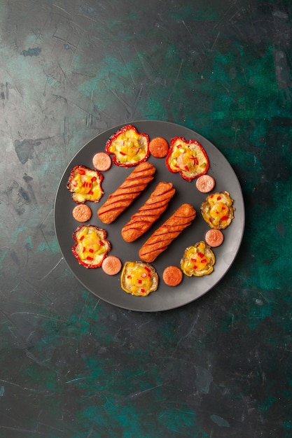 Gratis foto bovenaanzicht gekookte paprika met gebakken worstjes in plaat op donkergroen oppervlak