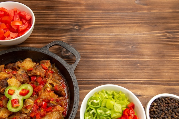 Bovenaanzicht gekookte plantaardige maaltijd met gesneden paprika salade op bruin oppervlak