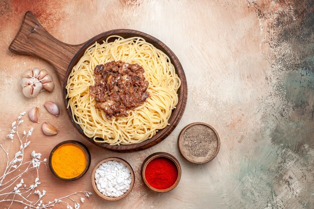 Bovenaanzicht gekookte spaghetti met gehakt op houten bureau pastadeegschotel kruiden