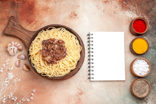 Bovenaanzicht gekookte spaghetti met gehakt op houten bureauschotel pastadeegkruiden