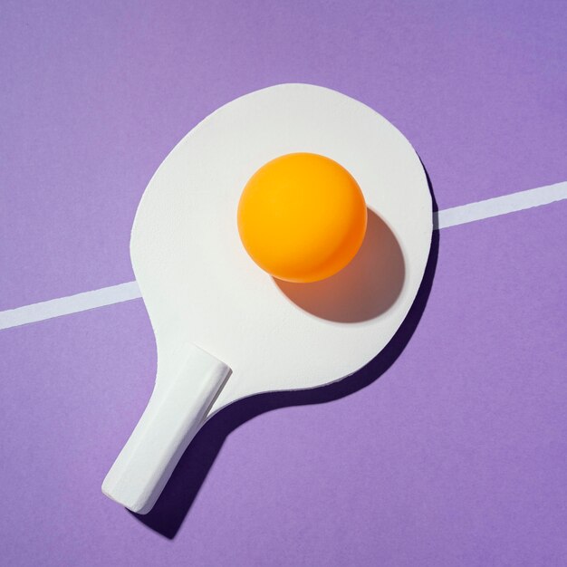 Bovenaanzicht gele bal op pingpongpeddel